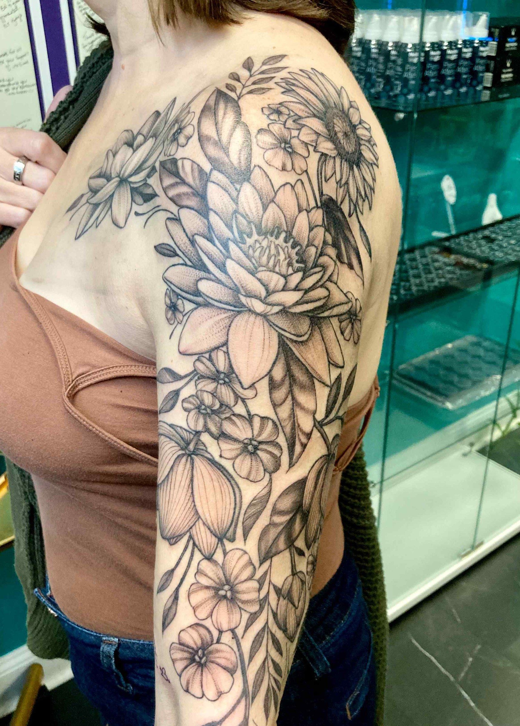 Black and grey floral half sleeve with lilies and peonies on a shoulder and upper arm