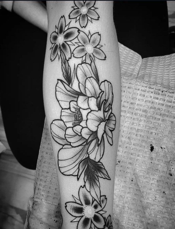 Black floral linework running down a forearm