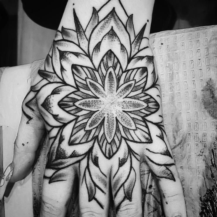 Black and grey mandala tattoo covering the back of a hand