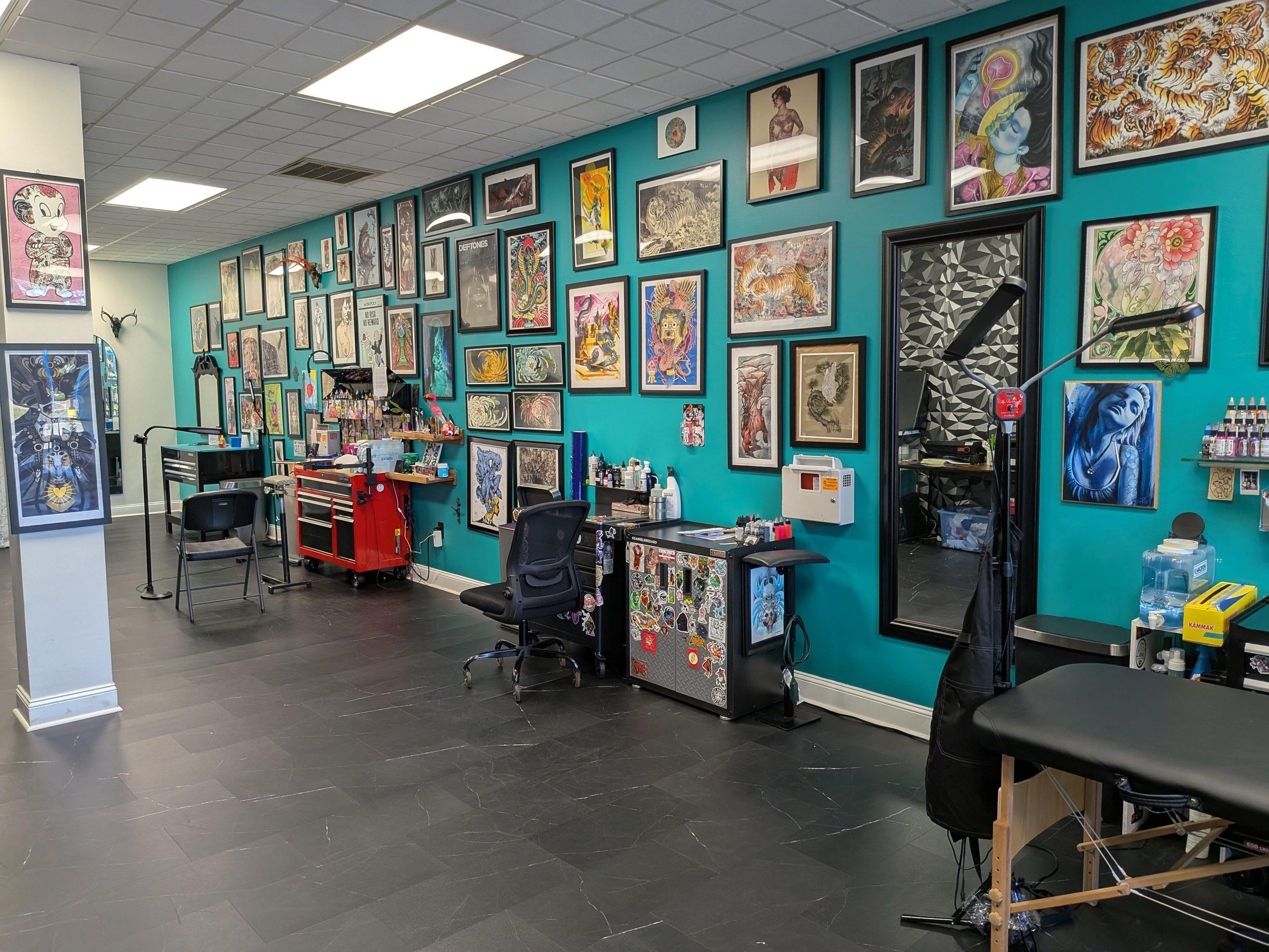 Inside Turquoise Panther Tattoo: turquoise walls lined with framed art and tattoo stations